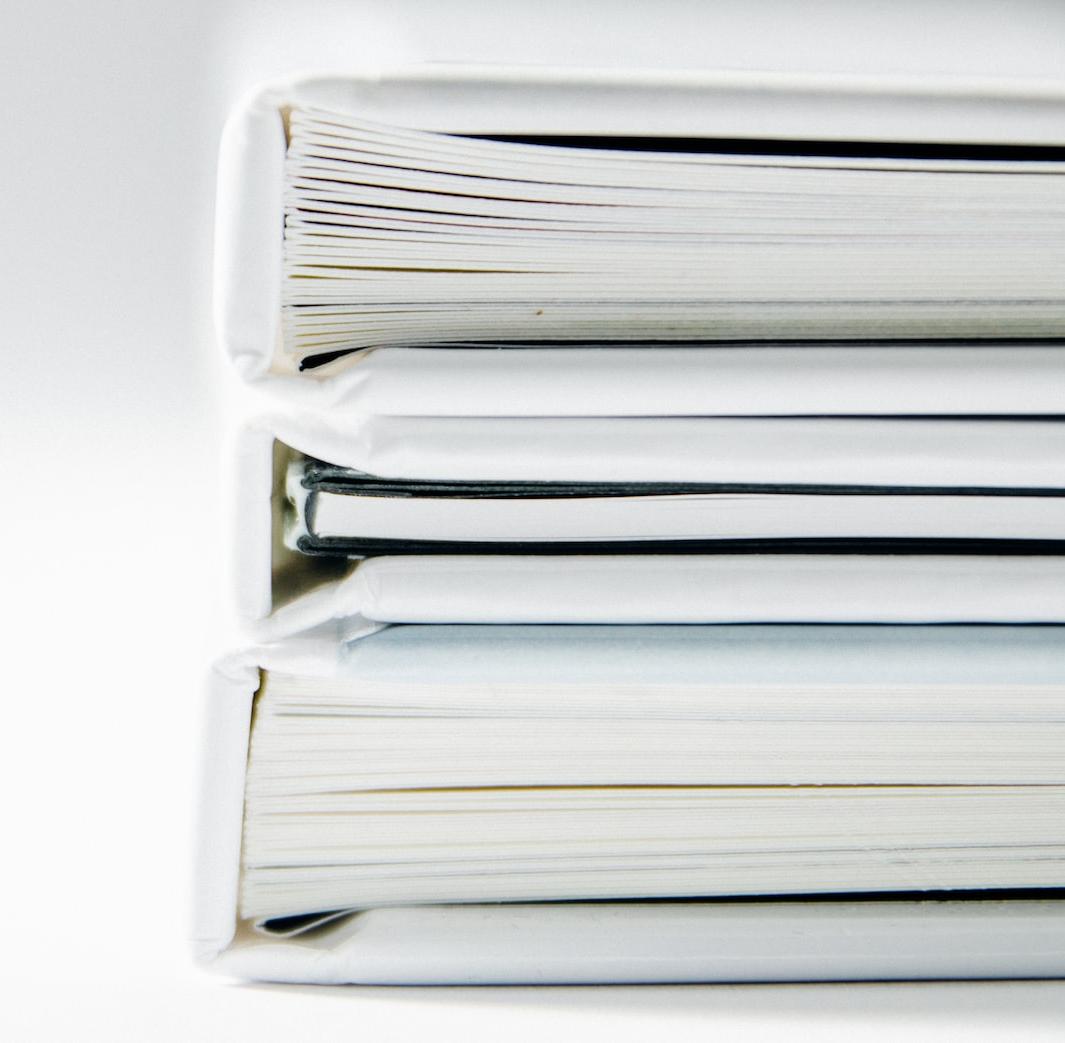A stack of thick folders on a white surface